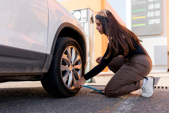 Woman check car tire pressure at gas station