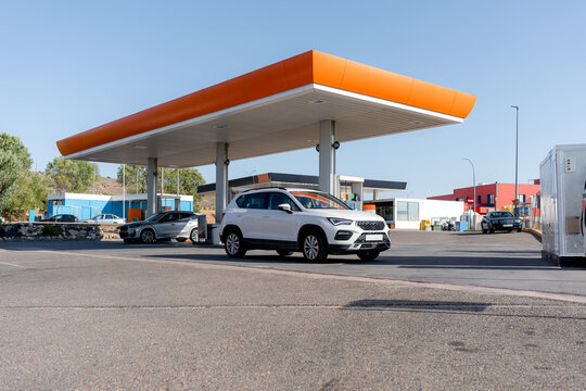 White SUV at gasoline station under orange canopy