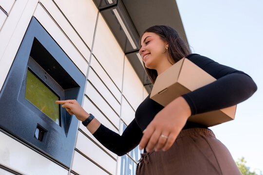 Woman send package through parcel locker at gas station