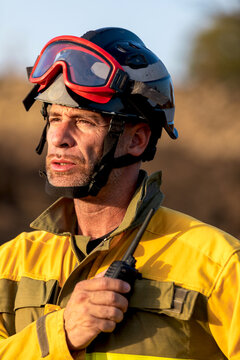Firefighter in protective gear holding radio outdoors