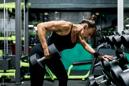 Woman perform dumbbell row workout in modern gym