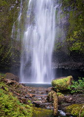 Upper Multnomah Falls cascades over a mossy basalt cliff into a rocky pool within the Columbia River Gorge in Oregon. © steheap