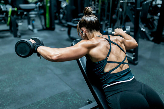 Woman perform dumbbell lateral raise at gym