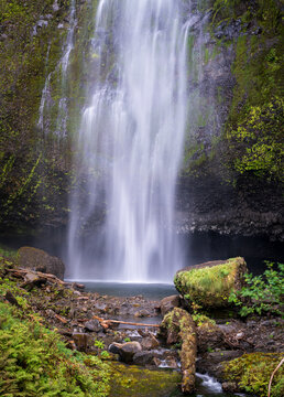 Upper Multnomah Falls cascades over a mossy basalt cliff into a rocky pool within the Columbia River Gorge in Oregon.