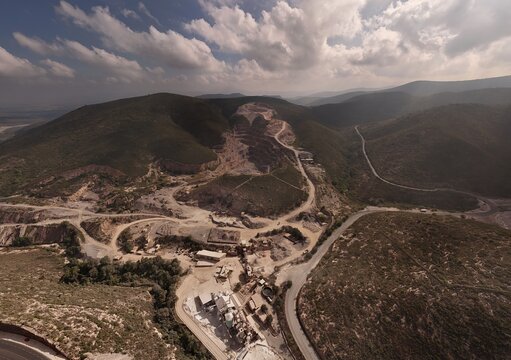 Toliman Municipality, Queretaro, Mexico - 19 September 2026: Aerial view of Caleras de Bernal quarry with industrial mining operations, terraced hillsides, and winding roads in an arid landscape.