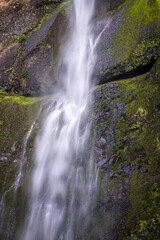 Water cascades down the mossy basalt cliff at Upper Multnomah Falls in the Columbia River Gorge National Scenic Area in Oregon. © steheap