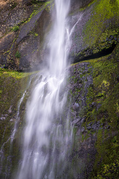Water cascades down the mossy basalt cliff at Upper Multnomah Falls in the Columbia River Gorge National Scenic Area in Oregon.