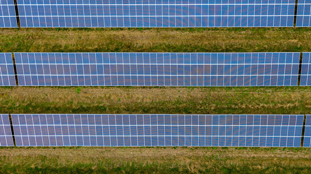 Fleet, United Kingdom - 18 September 2026: Aerial view of solar panels arranged in long rows across a grassy field.