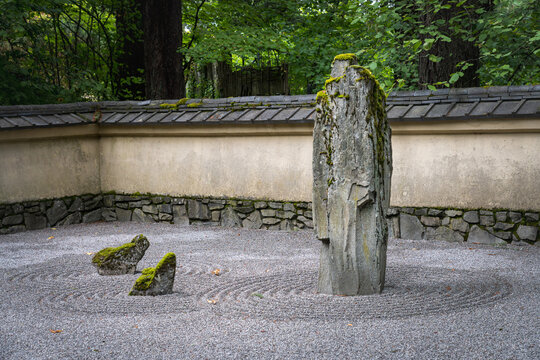 Zen rock garden featuring moss covered stones and raked gravel enclosed by traditional walls at the Portland Japanese Garden in Oregon.