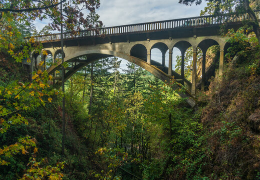 The historic Shepperds Dell concrete arch bridge carries the Historic Columbia River Highway through a forested gorge in Corbett, Oregon.