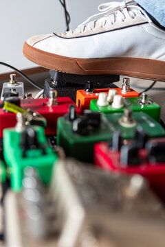 Musician foot on guitar effects pedalboard in studio