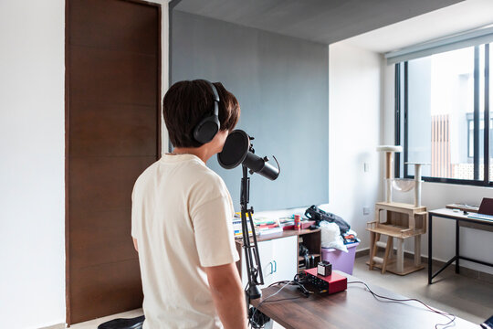 Young man record music with microphone in home studio