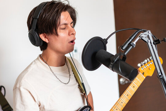Musician record vocal track with guitar in home studio