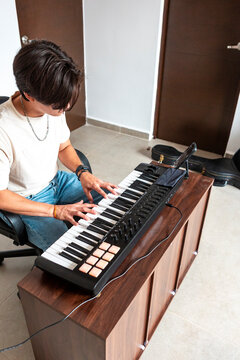 Young man compose music on electronic keyboard at home