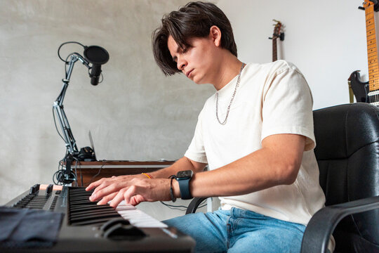 Music compositor playing keyboard in home recording studio