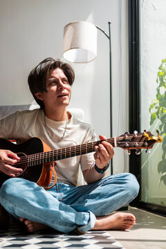 Music composer play acoustic guitar by sunlit window