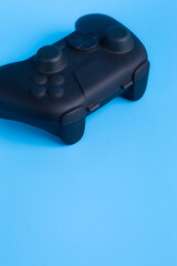 Vertical close up of angled black wireless gamepad on blue background with copy space. Ideal for social media gaming and esports ads.  © wibiwisnu