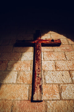 Wooden cross on ancient stone wall in dramatic light