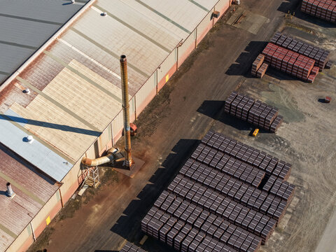 Melbourne, VIC, Australia - 18 September 2026: Aerial view of a brick manufacturing facility with stacks of bricks and pavers, an industrial building with a chimney, and a dirt yard.