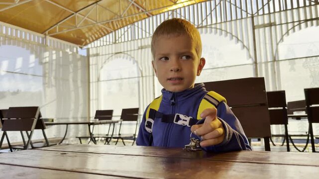 A young boy plays with a small toy at a wooden table in Valaam, Lake Ladoga. This quiet, thoughtful moment brings a calm, happy feeling of cozy vacation wonder.