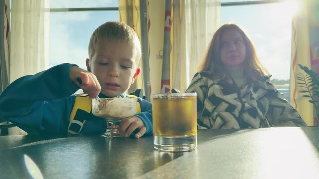A boy eats ice cream on a cruise ship at Lake Ladoga. This cozy moment brings a happy, joyful feeling of warm vacation comfort.