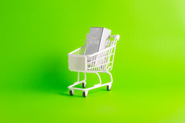 Buy fine silver bar in white shopping cart on green background for wealth investment concept.  © wibiwisnu