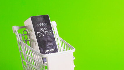 Close up angled view of fine silver bar in white shopping cart with copy space on green background for wealth investment.     © wibiwisnu