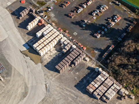Melbourne, Australia - 18 September 2026: Aerial view of a storage yard filled with stacks of bricks and pavers, arranged in organized rows on a gravel surface under clear daylight.