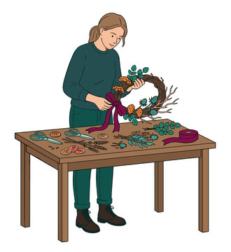 Woman making beautiful autumn wreath with natural elements and a vibrant ribbon on a rustic wooden table, showcasing her creative crafting process.