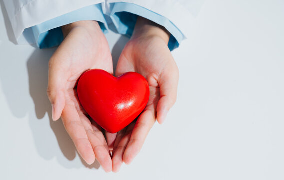 Doctor hands holding heart symbol for care and medical support expressing hopeful emotion