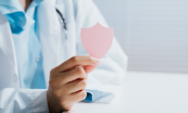 Doctor holding shield health insurance symbol, confident professional medic offering care with optimistic expression for patient safety