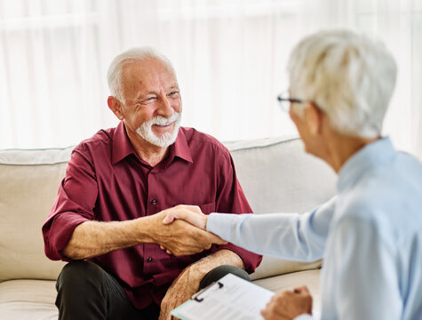 Portrait of a senior mature man lsitting in session with his female therapist or abusinessman shaking hands with a businesswoman making a deal