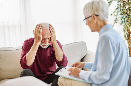 Portrait of a senior mature or mid aged man looking thoughtful or stressed and sad while sitting in session with his female therapist