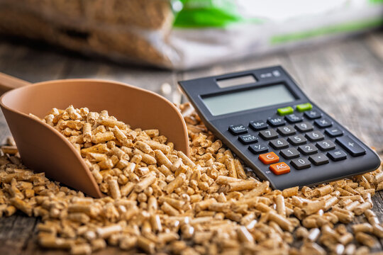 Wood Pellets And Calculator On Table Representing Biofuel Heating Costs And Renewable Energy Budgeting