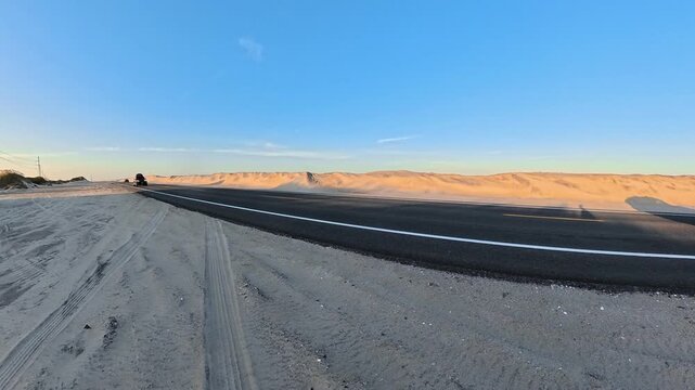 4K roadside video captures passing cars against a long ridge of sand.
