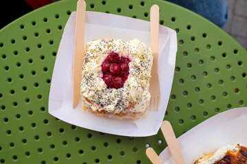 Cinnamon roll topped with cream cheese frosting, poppy seeds and berry jam, served outdoors at a park cafe, with natural grain. high quality photo © Татьяна Швец
