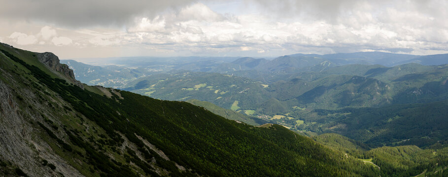 Panoramic View from a Steep Alpine Mountain Slope across Forested Valleys and Distant Peaks of the Rax Alps in Austria