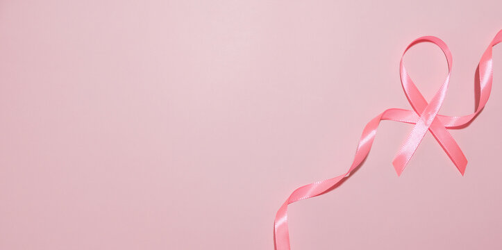 Pink breast cancer awareness ribbon on pink background