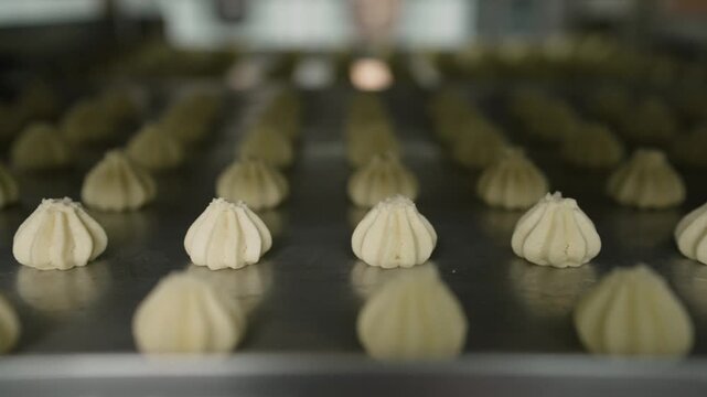 Close up tracking shot of piped cookie dough on a baking sheet before baking in a professional kitchen