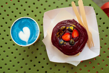 Cinnamon bun topped with berry glaze and fresh strawberries, served with blue matcha latte or lavender raf, cozy food styling with natural grain. high quality photo © Татьяна Швец