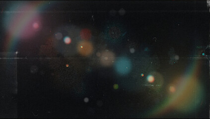 Fototapeta premium Abstract vintage dark film texture with soft colorful bokeh, pink and teal lens flare glow, orange and blue light circles, horizontal scratches, dust and heavy grain on a black background for overlays