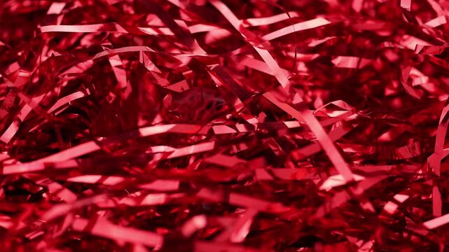 Gleaming red foil tinsel strips sparkle softly in close up view providing vibrant metallic decorative texture for romantic valentines day cards or elegant christmas celebration backdrops