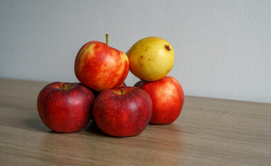 Red apples and a yellow pear are arranged on a wooden table. Concept of fruit, harvest, food, nutrition, abundance, freshness and still life setting © Анна Зеленая