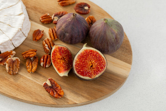Cheese figs and pecans arranged on a wooden board for a snack