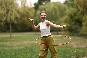 Athletic young woman exercising with hula hoop in park © New Africa