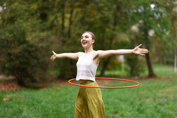 Athletic young woman exercising with hula hoop in park © New Africa