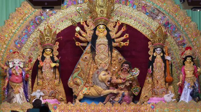 Maa Durga idol with attendant deities in a golden decorated pandal during Durga Puja festival