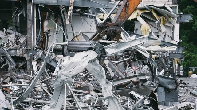 Excavator Arm Demolishing Building Amid Twisted Metal Rubble