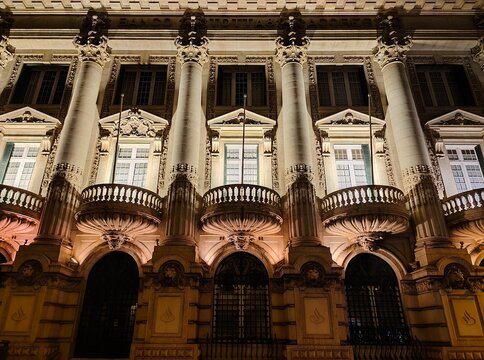 Low-angle view of the ornate Banco Totta and A&ccedil;ores building on Rua &Aacute;urea in Lisbon, Portugal, featuring grand Corinthian columns, sculpted balconies and warm night illumination.