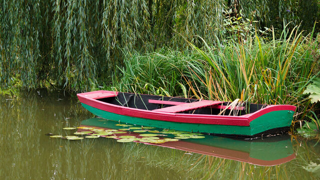 Barque rouge et verte au bord de l'eau dans une v&eacute;g&eacute;tation luxuriante